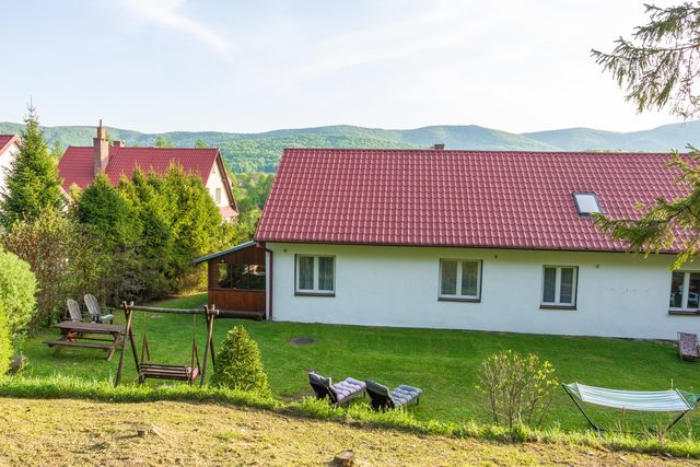 Budynek od strony ogrodu, z zadaszoną werandą i bieszczadzkimi szczytami w tle